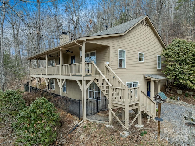 view of home's exterior with a deck, a chimney, ceiling fan, and stairs