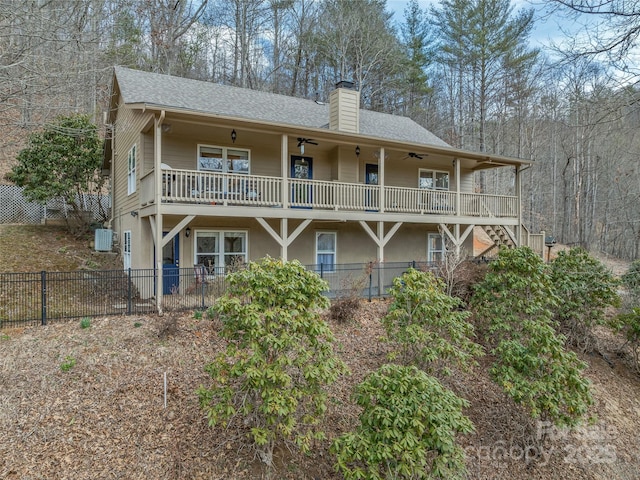 rear view of property with stairway, a ceiling fan, fence, roof with shingles, and a chimney