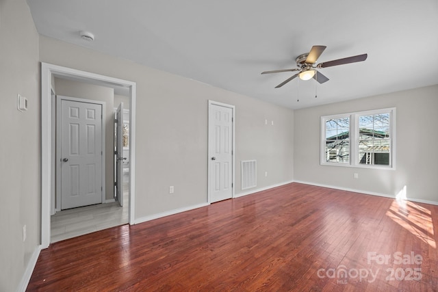 empty room featuring visible vents, baseboards, and wood finished floors