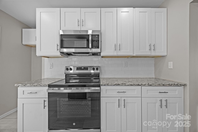 kitchen featuring appliances with stainless steel finishes, white cabinetry, decorative backsplash, and light stone countertops