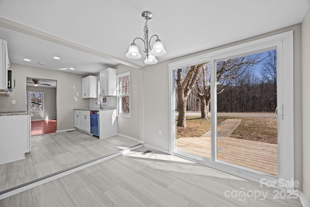 unfurnished dining area with recessed lighting, a sink, baseboards, and ceiling fan with notable chandelier