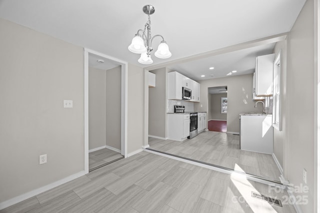 kitchen featuring stainless steel appliances, backsplash, white cabinetry, and baseboards