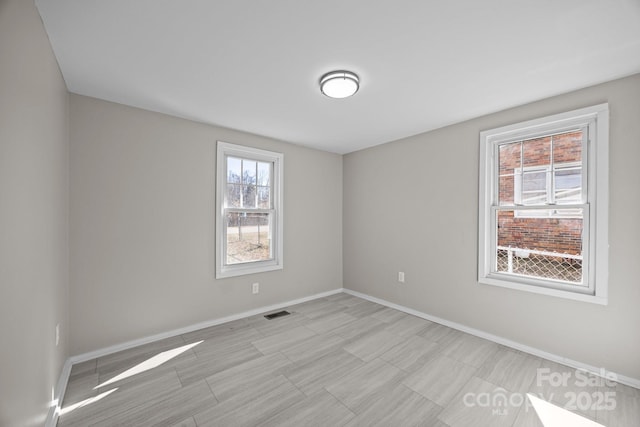 empty room featuring baseboards and visible vents