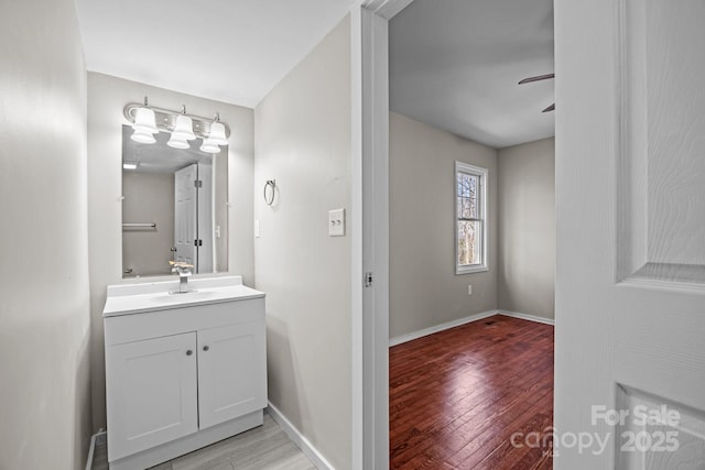 bathroom featuring ceiling fan, vanity, baseboards, and wood finished floors