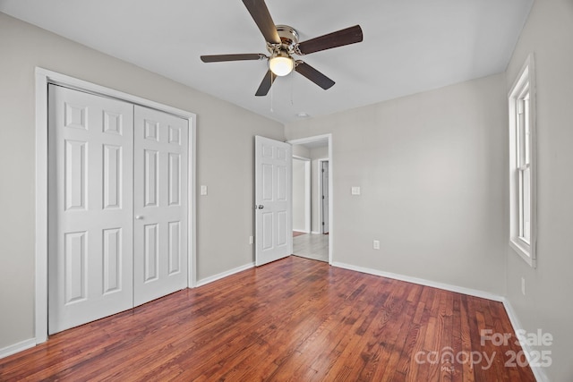 unfurnished bedroom with a closet, wood finished floors, a ceiling fan, and baseboards