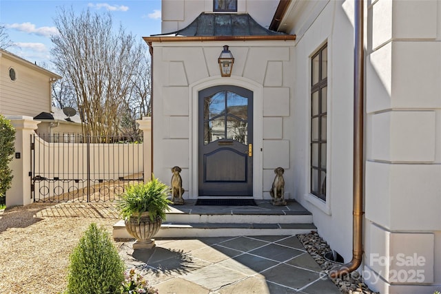 view of exterior entry featuring metal roof, a standing seam roof, and stucco siding