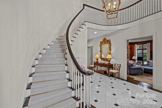 staircase with a chandelier, tile patterned flooring, a towering ceiling, and baseboards