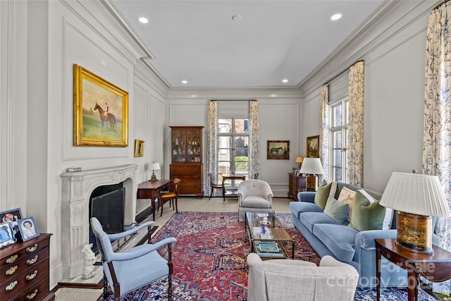 sitting room featuring ornamental molding, a fireplace, recessed lighting, and a decorative wall