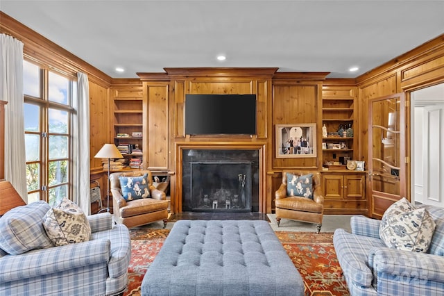 living room with wooden walls, a fireplace with flush hearth, built in shelves, and recessed lighting