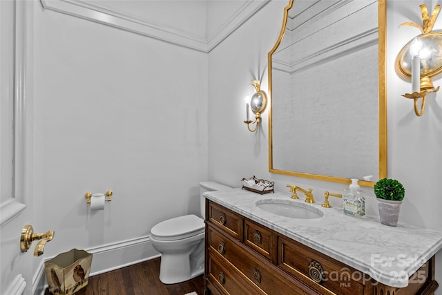 half bath with vanity, toilet, and wood finished floors