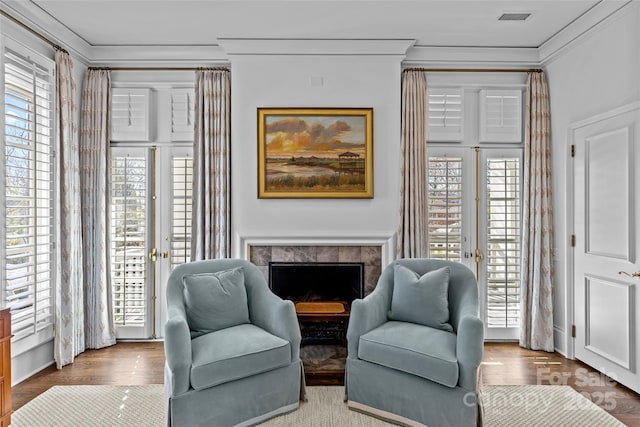 sitting room with french doors, a fireplace, visible vents, and crown molding