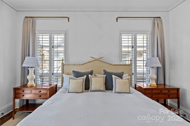 bedroom featuring multiple windows, baseboards, and wood finished floors