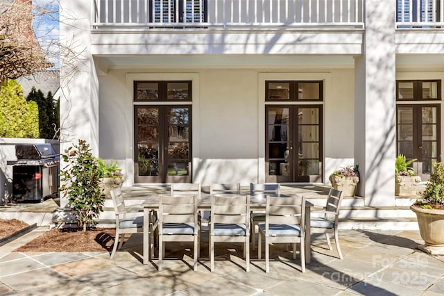 view of patio featuring a balcony, outdoor dining space, area for grilling, and french doors