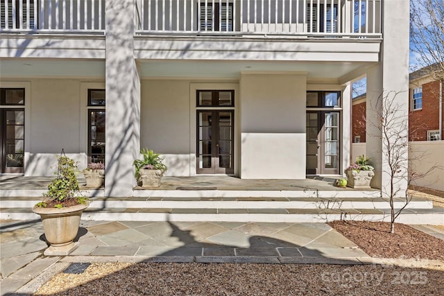 entrance to property with a balcony, covered porch, and stucco siding