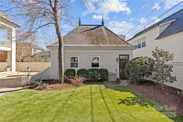 rear view of property featuring central AC, a yard, fence, and stucco siding