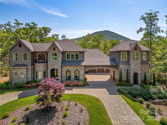 1905 White Tree Trl, Arden, NC 28704 - french country home featuring stone siding, curved driveway, a mountain view, stucco siding, and a front lawn