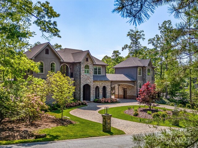 1905 White Tree Trl, Arden, NC 28704 - french country home featuring curved driveway, stone siding, a front yard, and stucco siding