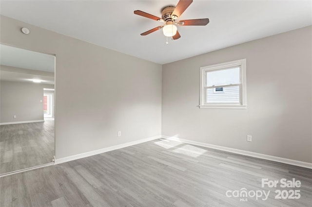 empty room with baseboards, wood finished floors, a ceiling fan, and a healthy amount of sunlight