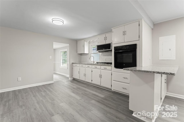 kitchen with stainless steel appliances, backsplash, light wood-style floors, white cabinets, and electric panel