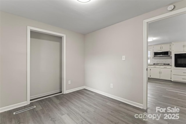 interior space featuring baseboards, visible vents, and wood finished floors