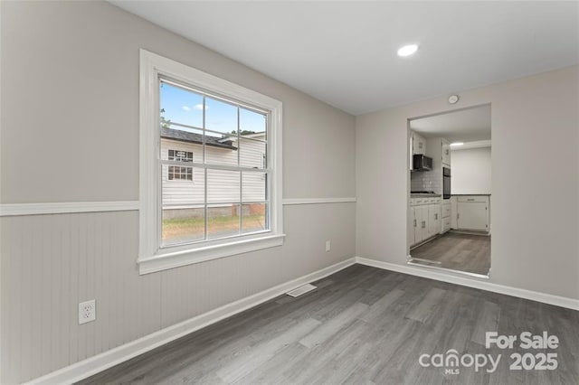 spare room featuring dark wood-type flooring, recessed lighting, visible vents, and baseboards