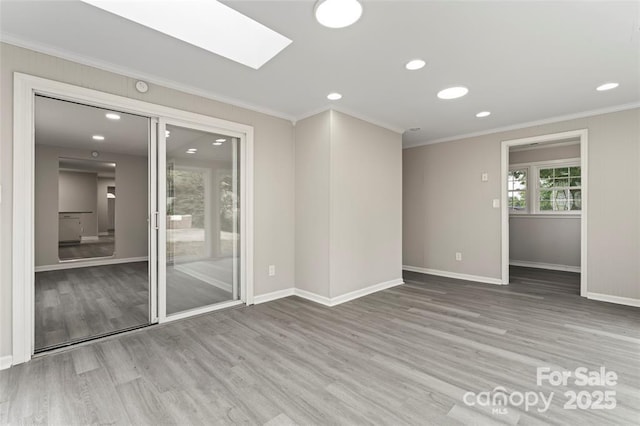 unfurnished room with a skylight, crown molding, and wood finished floors