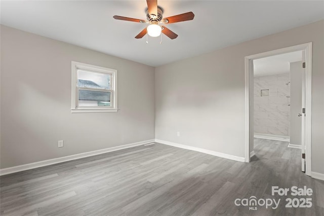 spare room with ceiling fan, wood finished floors, and baseboards