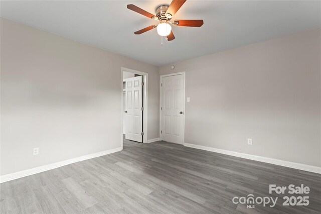 spare room featuring ceiling fan, wood finished floors, and baseboards