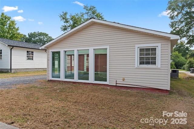 back of property with central AC unit and a yard