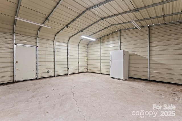 garage featuring freestanding refrigerator and metal wall