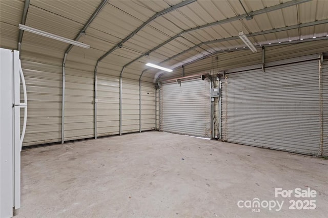 garage featuring freestanding refrigerator and metal wall