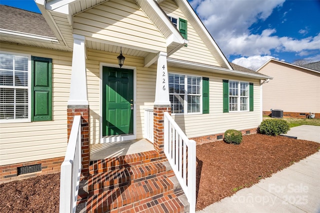 property entrance with crawl space, central AC, and a shingled roof