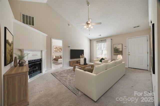 living room with a fireplace with flush hearth, light colored carpet, visible vents, and a textured ceiling