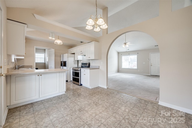 kitchen with range with two ovens, light carpet, arched walkways, and ceiling fan