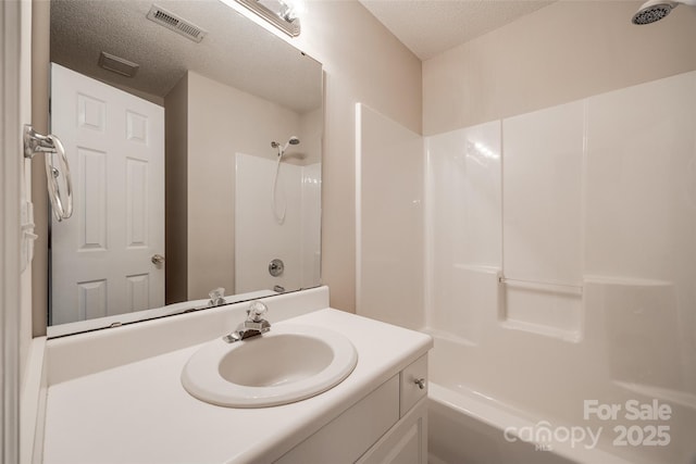 full bathroom featuring visible vents, a textured ceiling, vanity, and  shower combination