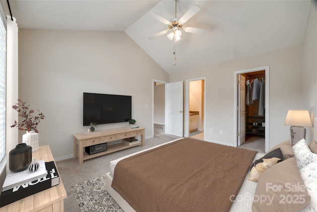 bedroom with a walk in closet, baseboards, light colored carpet, lofted ceiling, and ensuite bath