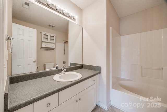 bathroom featuring visible vents, toilet, vanity, bathing tub / shower combination, and a textured ceiling