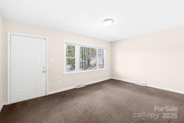 unfurnished room featuring baseboards, visible vents, and dark carpet