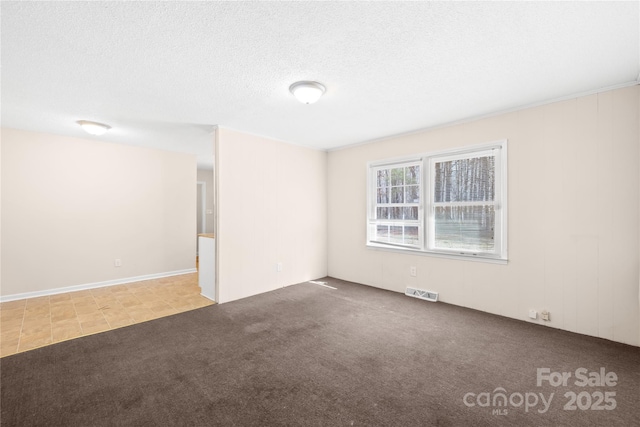 empty room with carpet flooring, visible vents, and a textured ceiling