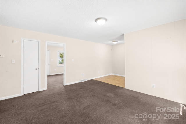 carpeted empty room with visible vents and a textured ceiling