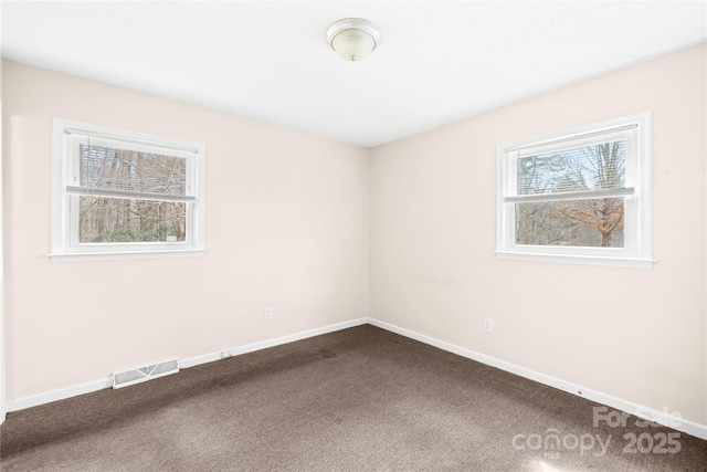 empty room featuring visible vents, baseboards, and dark carpet