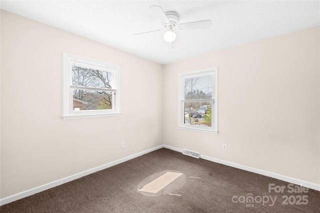 carpeted empty room with visible vents, baseboards, and a ceiling fan