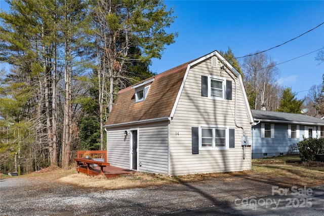 view of side of home with roof with shingles and a gambrel roof