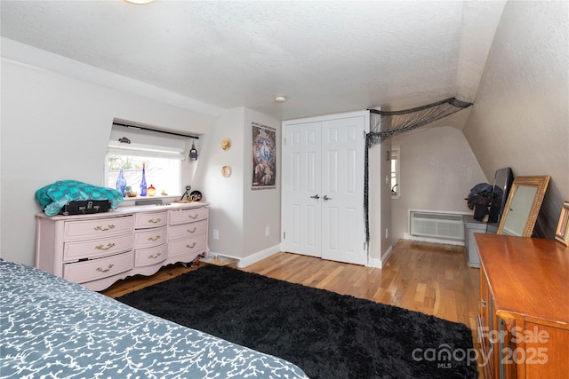 bedroom featuring a textured ceiling, a closet, wood finished floors, and baseboards