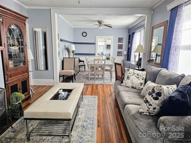 living room with ceiling fan, baseboards, wood finished floors, and crown molding