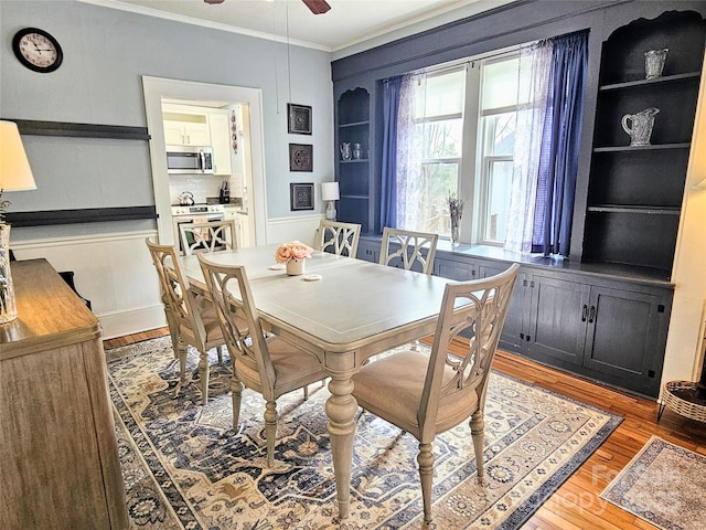 dining area with light wood-type flooring, ceiling fan, built in shelves, and ornamental molding