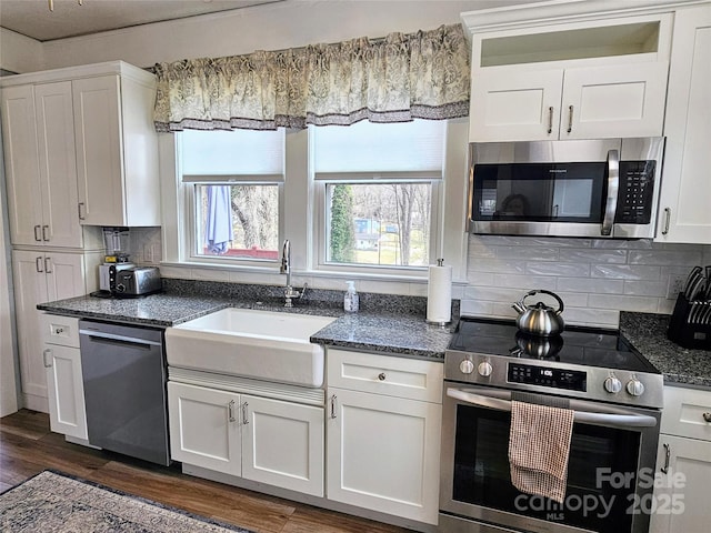 kitchen featuring appliances with stainless steel finishes, dark wood-type flooring, a sink, and white cabinetry