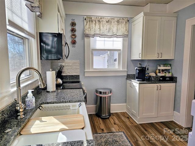 kitchen featuring dark wood-style floors, tasteful backsplash, white cabinets, a sink, and baseboards