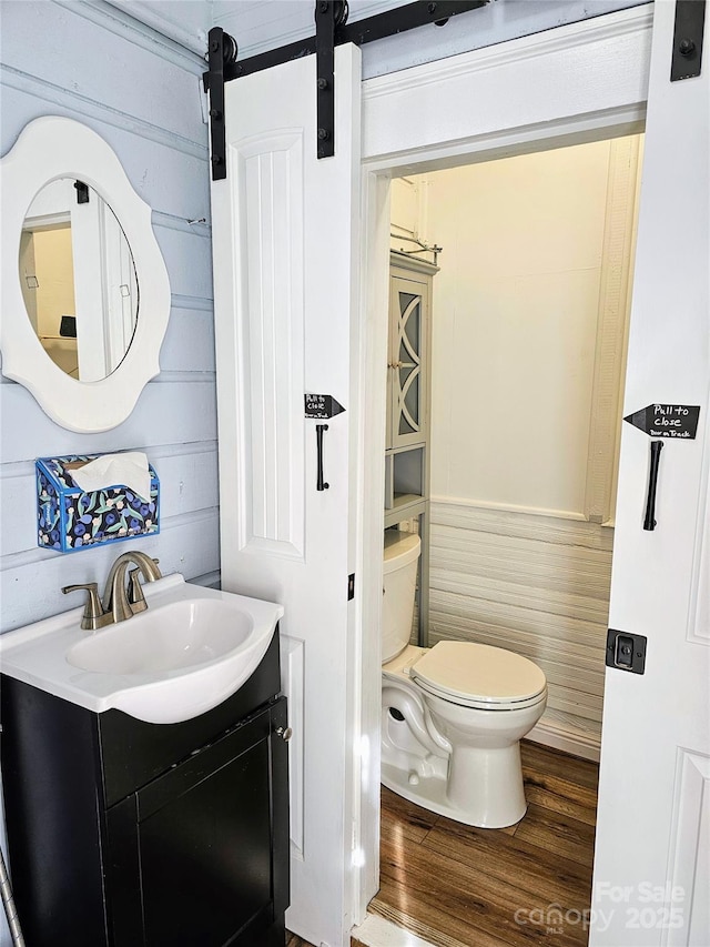 half bathroom featuring toilet, wood finished floors, and vanity