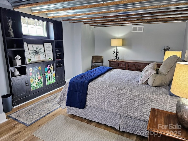 bedroom featuring beam ceiling, visible vents, and wood finished floors